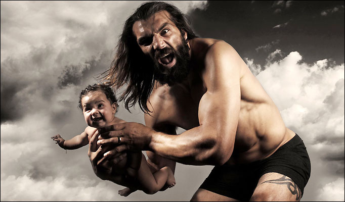 French (France) rugby player Sebastien Chabal in his pants holding a baby.  It's possibly his lunch.