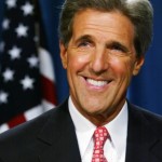 John Kerry pictured wearing a red tie in front of the Stars and Stripes (US / USA flag) with pink lips / pink lipstick ?